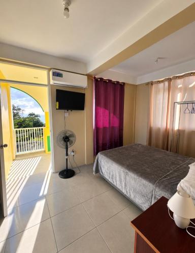 a hotel room with a bed and a balcony at Barefoot Apartments in Roseau