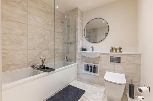 a bathroom with a tub and a toilet and a mirror at Luxury 2BR Apartment I Sleep 8 I Direct to Wembley & Euston in Hatch End