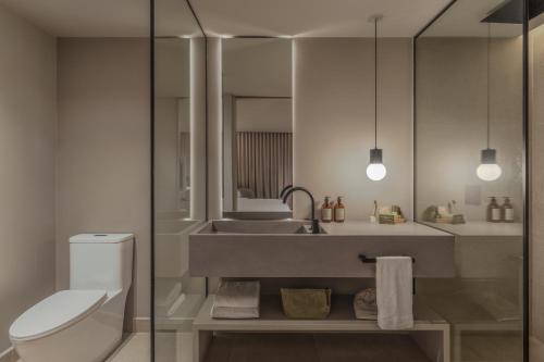 a bathroom with a sink and a toilet and a mirror at Wake BioHotel, a Member of Design Hotels in Medellín