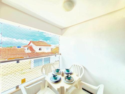 a white room with a table and chairs and a window at Apartamento com varanda e VISTA para RUA, TV e 2 suítes in Teixeira de Freitas