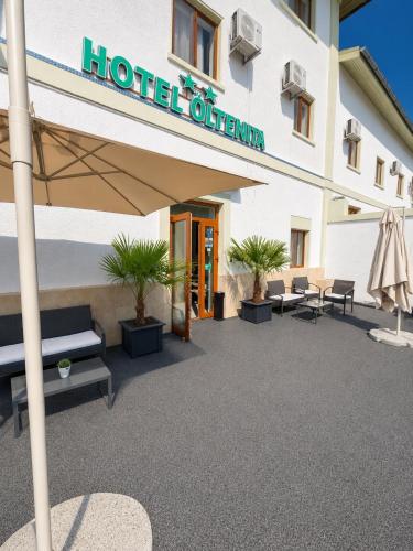 a hotel exterior with tables and chairs and an umbrella at Hostel Oltenia in Eforie Sud