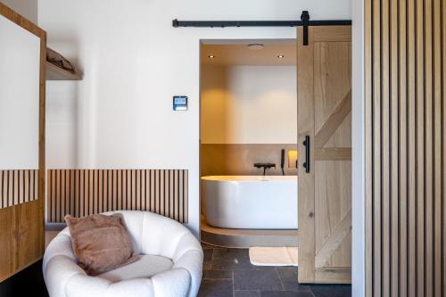 a bathroom with a tub and a chair and a bath tub at Burgemeestershof in Wetteren