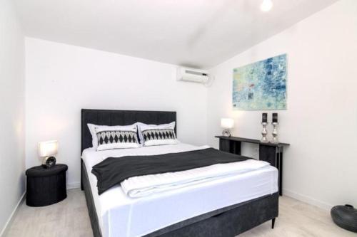 a white bedroom with a large bed and two tables at House Nika in Punat