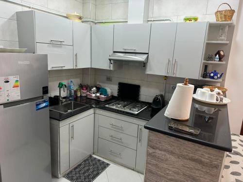 a kitchen with white cabinets and a black counter top at Appartement in Jijel