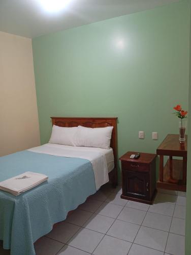 a bedroom with a bed with a blue blanket and a table at Hotel del angelinn in Martínez de La Torre