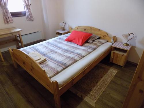 a bedroom with a wooden bed with a red pillow at Apartment Zeleni dragulj Pohorje in Oplotnica