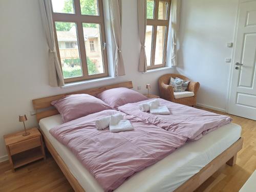 a bedroom with a large bed with pink sheets and pillows at Logierhaus Hoppegarten direkt an der Rennbahn mit perfekter S-Bahn Anbindung in Hoppegarten