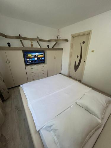 a bedroom with a large white bed and a tv at Apartament The Infinity Nest in Târgu Jiu