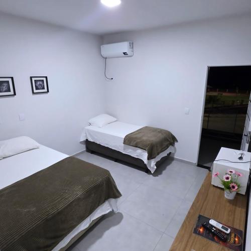a hotel room with two beds and a television at Trilhas do Araguaia in Aruanã