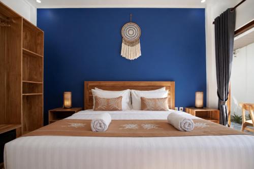 a bedroom with a large bed with a blue wall at Luciana Hotel in Labuan Bajo