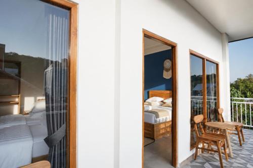 a bedroom with a balcony with a bed and a table at Luciana Hotel in Labuan Bajo