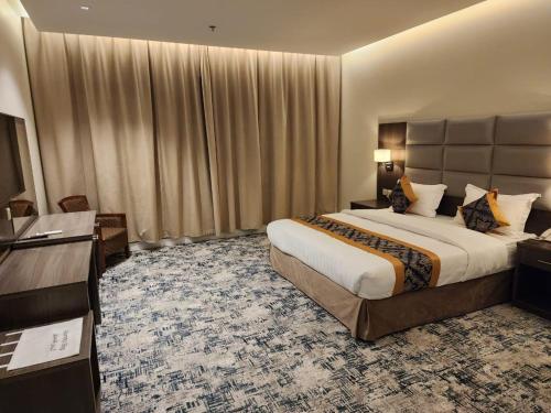 a hotel room with a large bed and a desk at فندق الفال الشمالي الفندقية in Ḑubā