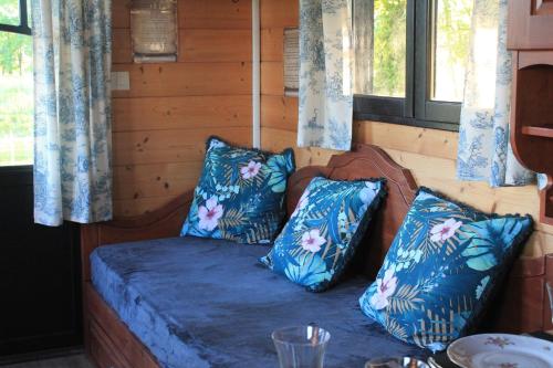 a bed in a room with two blue pillows at roulotte de charme avec jacuzzi privé in Beaupouyet