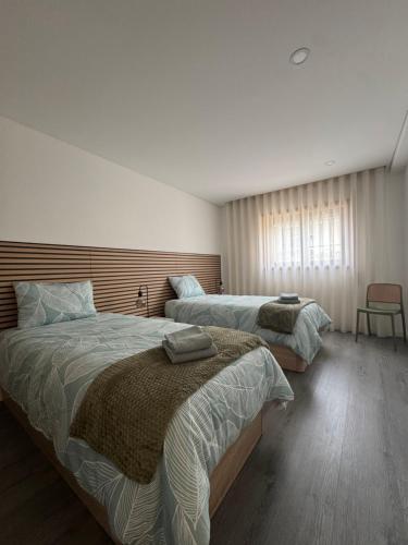 a bedroom with two beds and a window at Refúgio da Barra in Gafanha da Nazaré