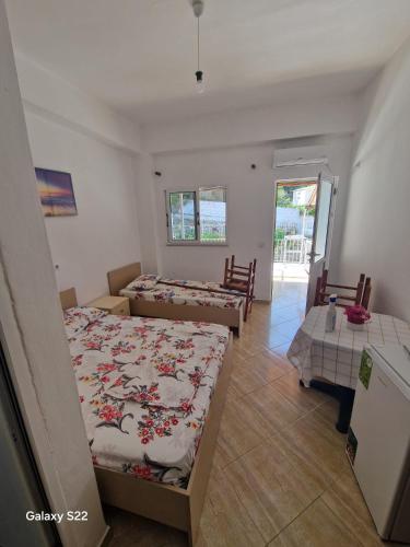 a bedroom with two beds and a table and chairs at Sunset Panorama Residence in Vlorë