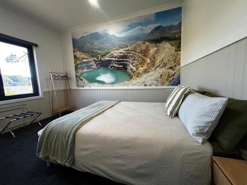 a bedroom with a bed with a painting on the wall at The Cozy Cottage-With elevated views in Queenstown