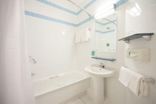 a bathroom with a sink and a tub and a toilet at Leonardo Hotel Derby in Derby