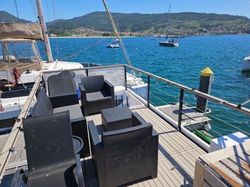 a deck of a boat with chairs on the water at Duerme en un barco in Moaña