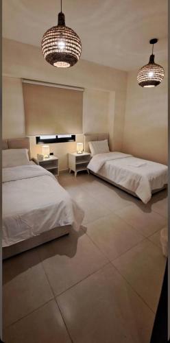 a bedroom with two beds and two lights and two tables at غرفتين وصالة شقق ديما الفندقية in Abha