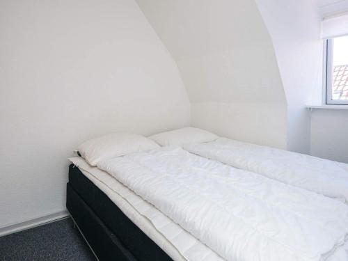 a bed in a room with white walls and a window at 2 person holiday home in Ringkøbing in Ringkøbing