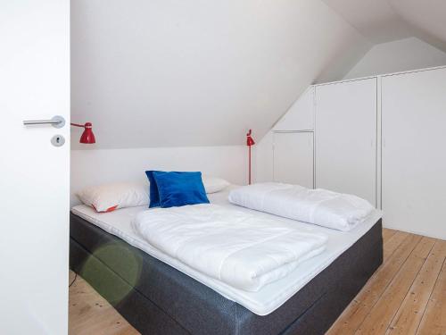a bed with white and blue pillows in a room at Holiday home in Ringkobing in Ringkøbing