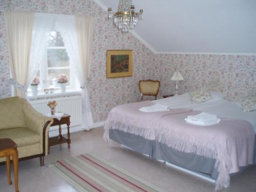 a bedroom with a bed and a chair and a window at Åkerby Herrgård in Nora