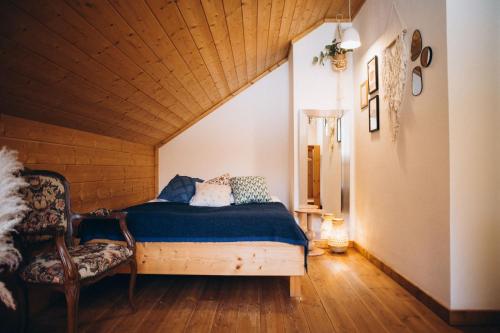 a bedroom with a bed and a chair in a room at Siedlisko Rogówko in Rogówko