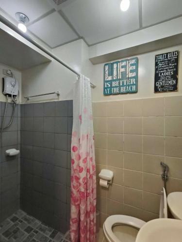 a bathroom with a shower and a toilet and a sign at Maldee's Place Tagaytay Prime Residences in Tagaytay
