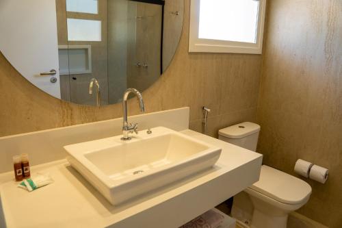 a bathroom with a sink and a toilet and a mirror at Beach Hotel Paúba in São Sebastião