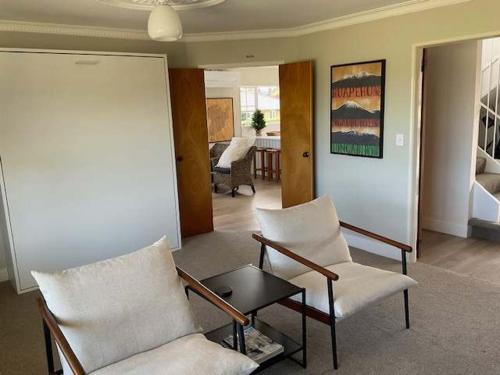 a living room with two chairs and a table at Fletcher House Sleeps 18 Location Views in Taupo