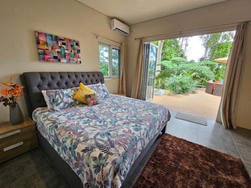 a bedroom with a bed and a large window at Seven on the Hillside in Pacific Harbour