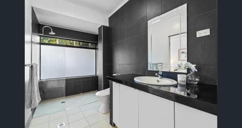 a bathroom with a sink and a toilet and a window at Stylish Tropical Villa with Lagoon Pool in Port Douglas