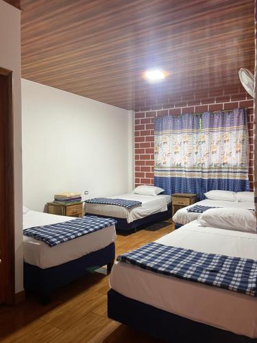 a room with three beds and a brick wall at Sisa Lodge in Tena