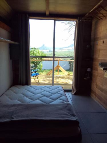 a bedroom with a bed and a large window at Chalé amora Analândia in Analândia