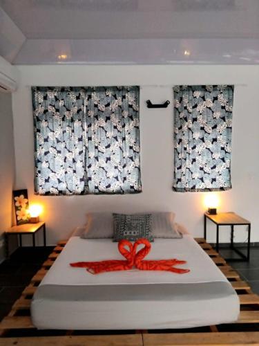a bedroom with a bed with a red ribbon on it at Fare Zen Raiatea - with pool in Uturoa