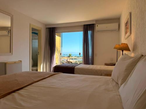 a hotel room with two beds and a view of the ocean at Hotel Pousada Casacolina in Búzios