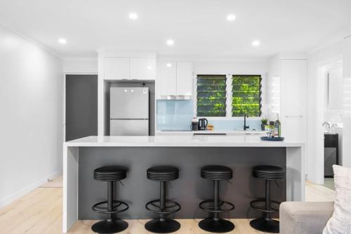 a kitchen with a counter with stools under it at Azure beachside Escape in Marcoola