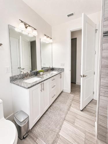 a white bathroom with two sinks and a mirror at SpaceX R4 Shared in Orlando