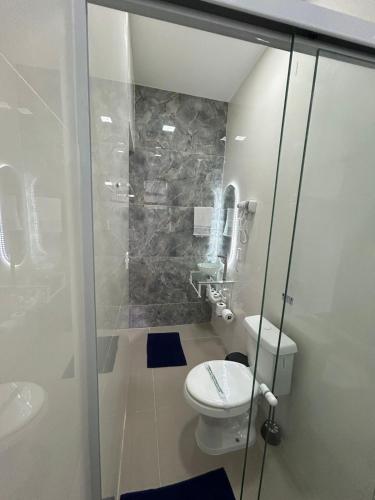 a bathroom with a toilet and a glass shower at Studio CG Tingui 1 in Estação Inhoaíba