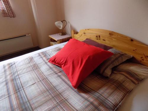 a bed with a wooden headboard and a red pillow at Apartment Zeleni dragulj Pohorje in Oplotnica