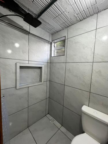 a bathroom with a toilet and a window at Hostel e Pousada das Rosas Nova Hartz RS in Nova Hartz