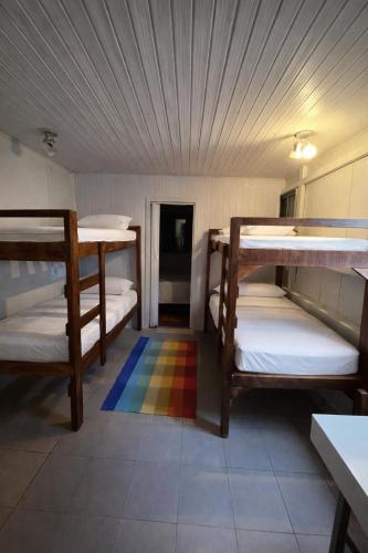 a room with three bunk beds and a rainbow rug at Hostel e Pousada das Rosas Nova Hartz RS in Nova Hartz
