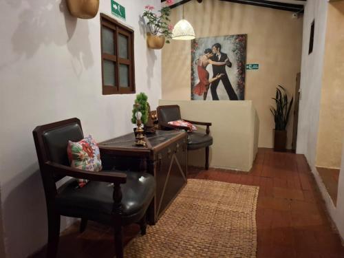 a living room with two chairs and a desk and a painting at Hotel Alma Divina in Villa de Leyva