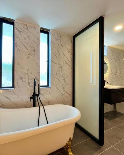 a white bath tub in a bathroom with windows at Alva Boutique Chalet Pangkor in Pangkor