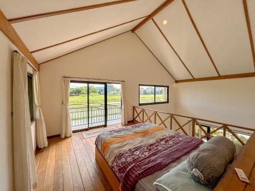 a bedroom with a bed and a balcony at Villa Umah Dangin Desa in Tanah Lot