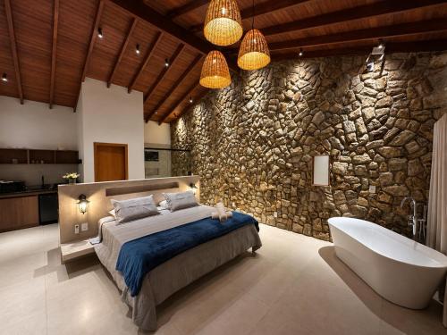 a bedroom with a bed and a bath tub and a stone wall at Pousada Yvanna in Pirenópolis