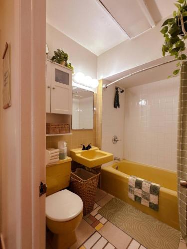 a bathroom with a yellow tub and a toilet and a sink at Bluffton Breeze Cottage in Muskegon