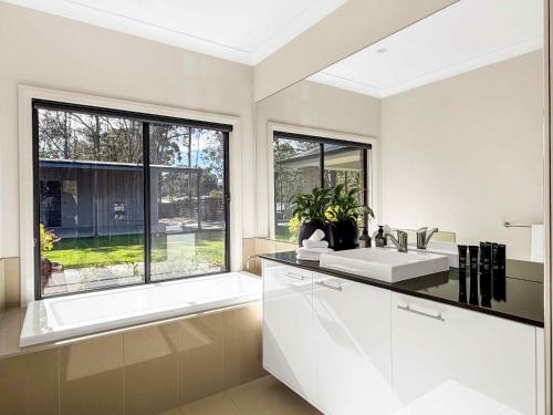 a white bathroom with a sink and a window at Wrenwood in Abernethy