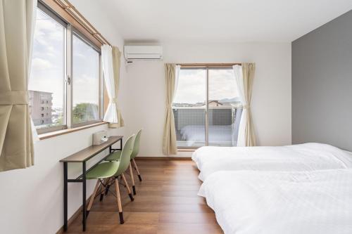 a bedroom with a bed and a desk and windows at Fujiyama Stay in Fujinomiya