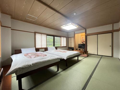 two beds in a room with two windows at Hotel Omodaka in Yamanouchi